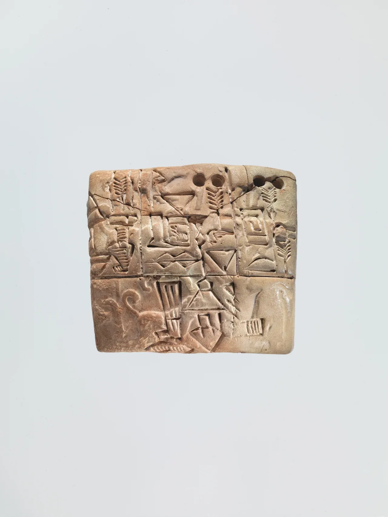 A thick clay accounting tablet with incised compartments, circular number marks, and shallow seal impressions.