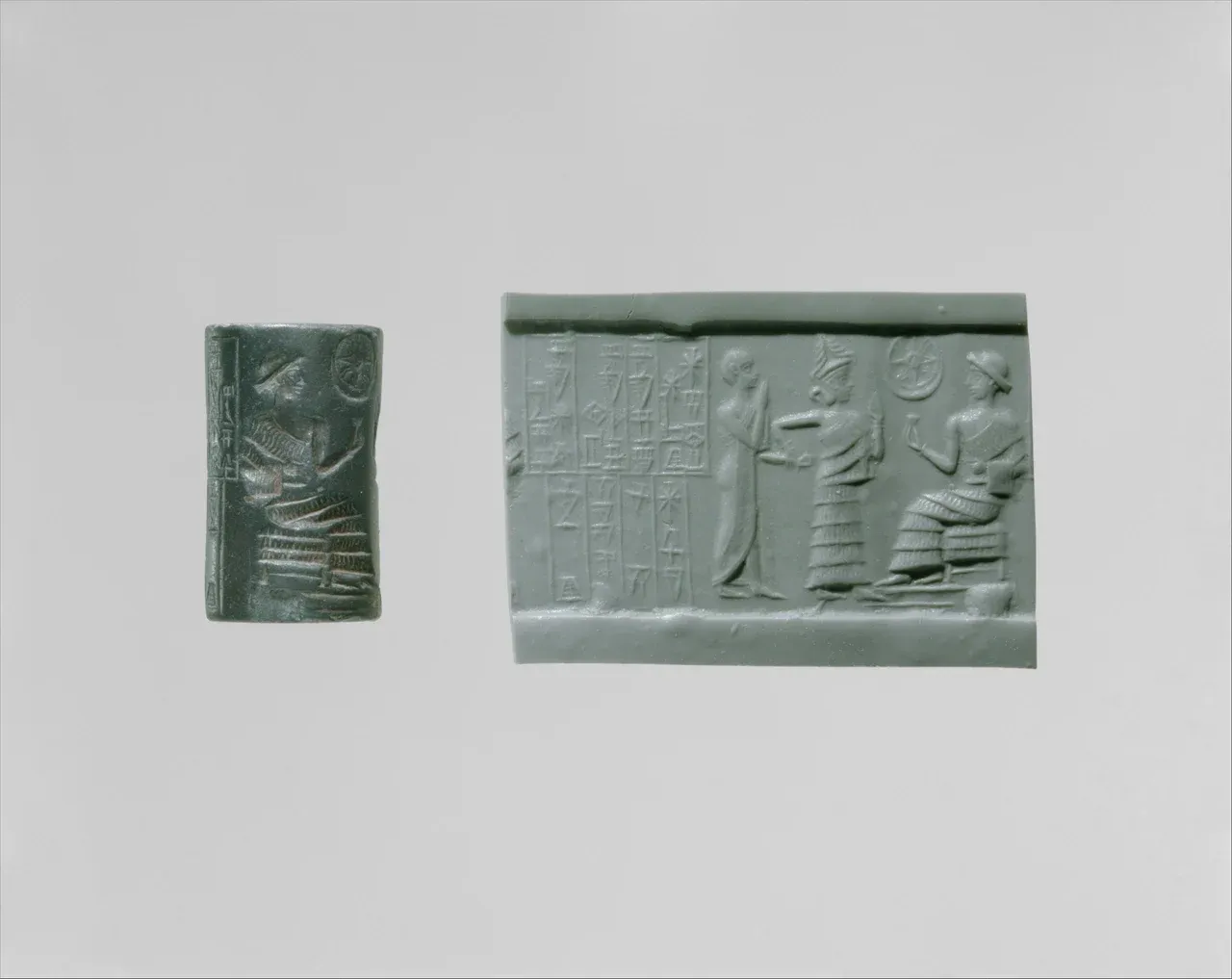 A dark cylinder seal beside a modern impression showing a goddess leading a standing worshiper towards a seated figure, with columns of cuneiform at the left.