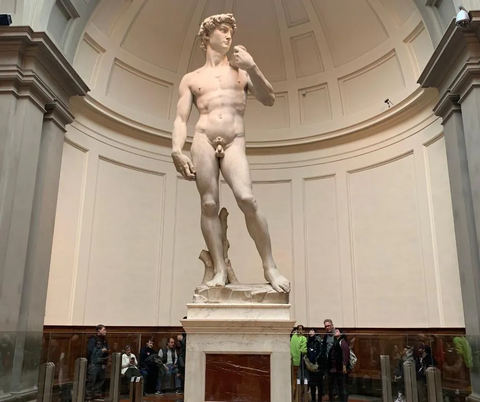 David under the domed apse of the Galleria dell’Accademia, visitors gathered at the foot of the plinth, small against him